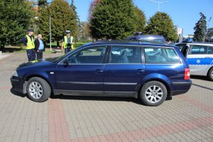 Policjanci stojący przy samochodzie VW Passat